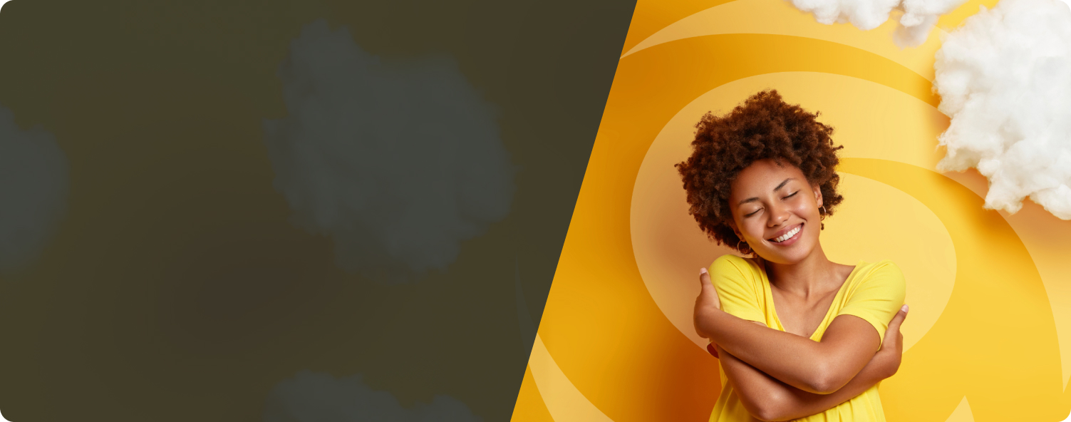 Young Black woman with auburn afro in a yellow shirt against yellow backdrop, hugging herself with dreamlike clouds around her head.