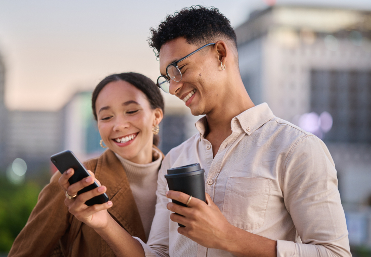 Young couple, male and female, smiling looking down at the male’s phone after starting the Golden Coast Finance’s QuickQualify program.