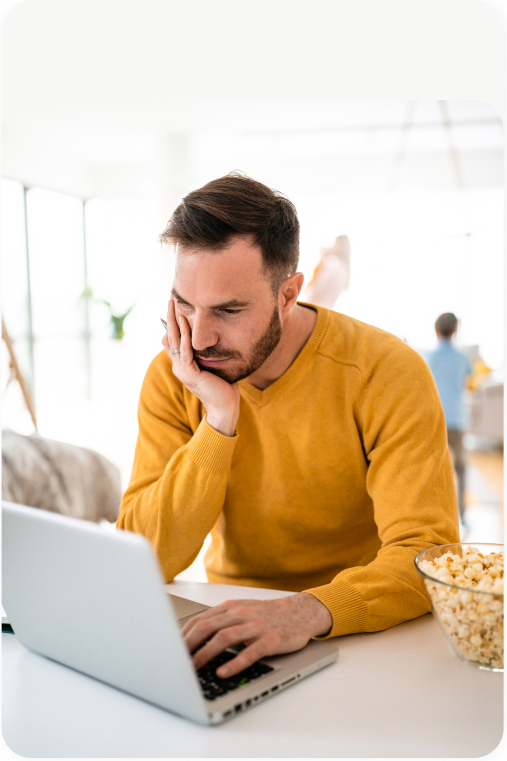 Male in bright yellow long sleeve shirt browsing the web for the perfect loan on a laptop.