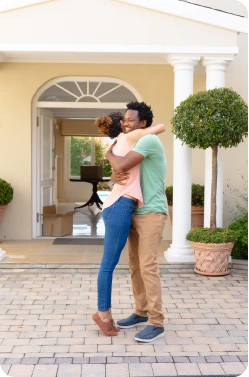 Black young couple embracing with happiness outside their new home.