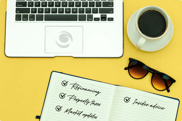 A desk with a laptop, coffee, sunglasses and a notepad with bullet points: refinancing, property taxes, market updates, and insider advice.